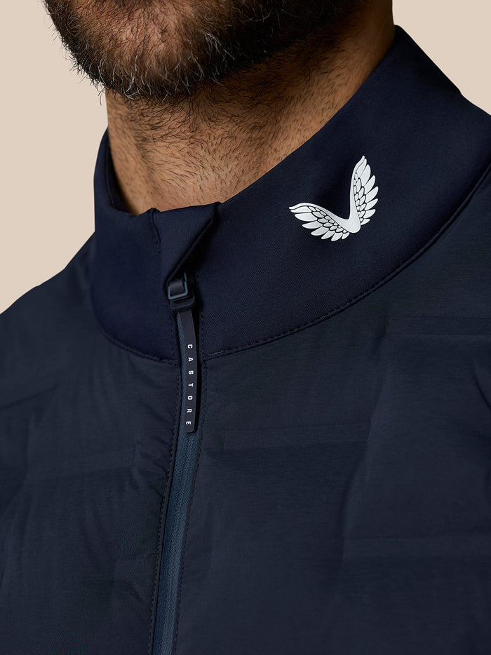 Close-up of navy gilet collar showing Castore wing logo and branded zipper pull