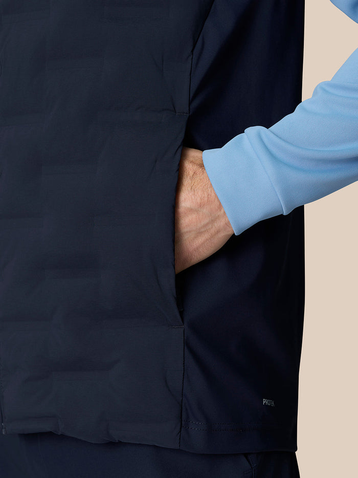 Side view of navy Pinnacle Gilet pocket with hand in pocket and light blue sleeve visible