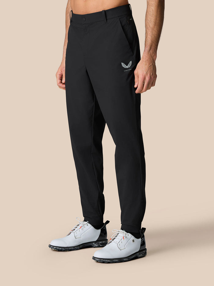 Male model in black golf trousers with zip cuffs and Castore branding on right thigh