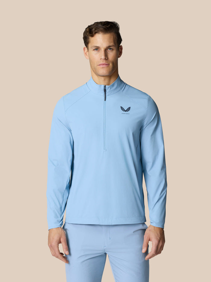 Man in sky blue Golf Flex Jacket with high funnel neckline and front half zip, Castore branding on chest and back