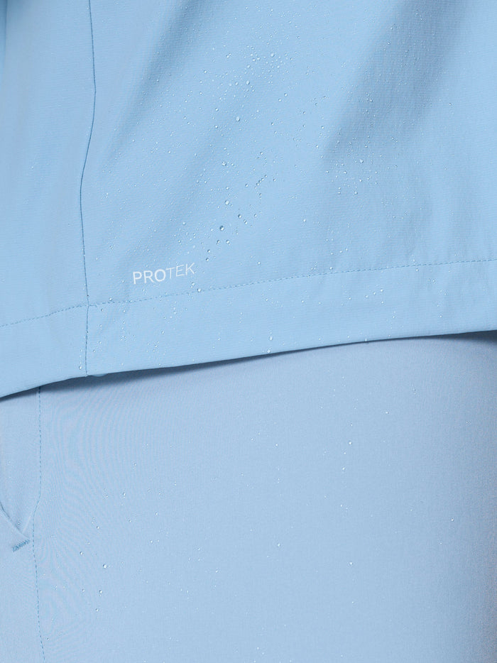 Close up of sky blue jacket fabric with water droplets and ProTek branding.