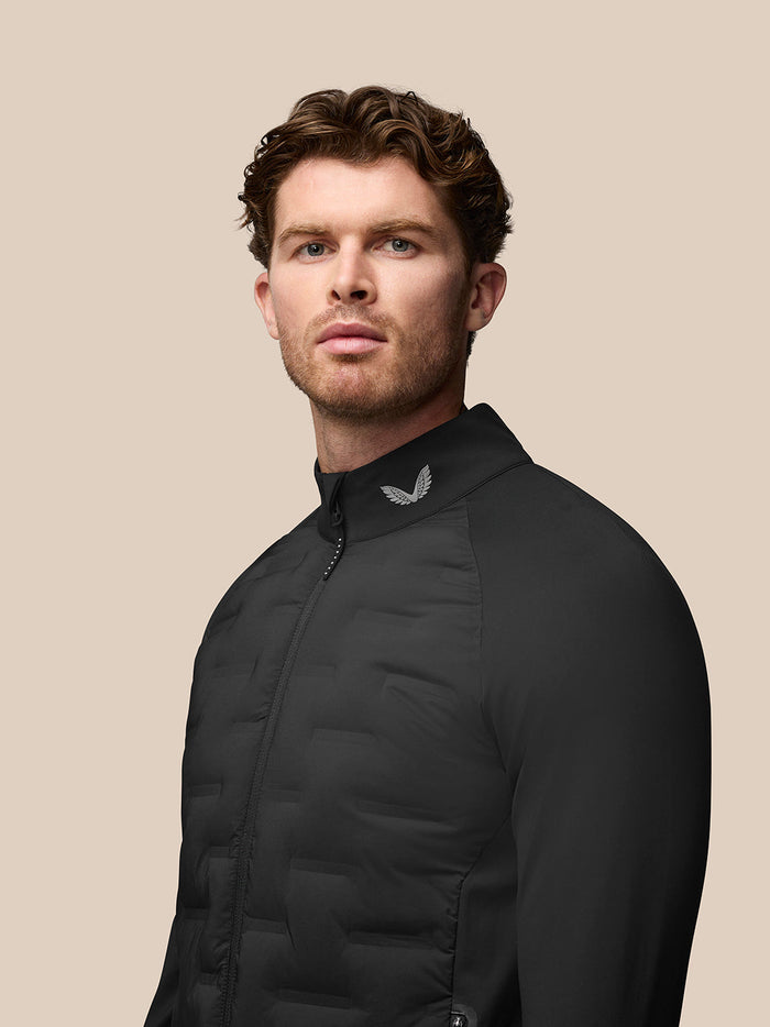 Portrait of a male model wearing black Pinnacle Golf Jacket with stand collar and wing logo