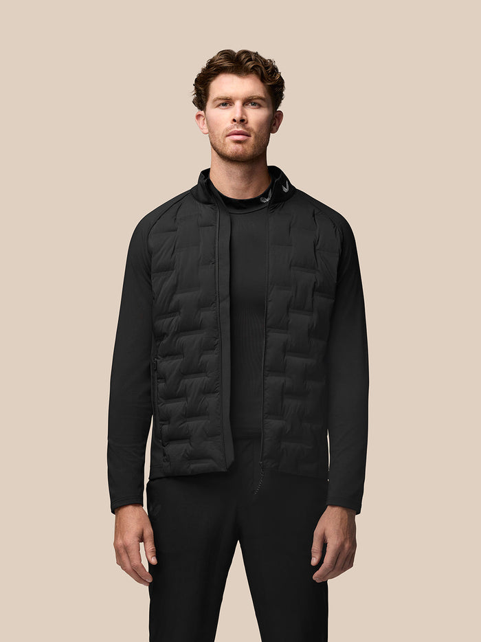 Model wearing black Pinnacle Golf Jacket with quilted front panels and stand collar.