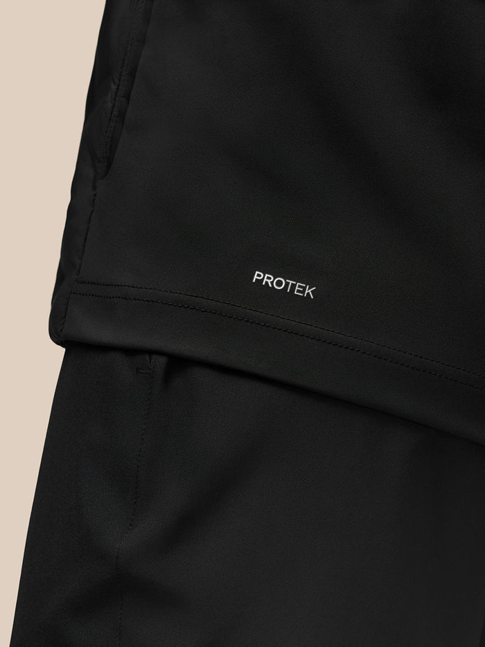Close-up of Protek branding on the hem of the black Golf Pinnacle Jacket.