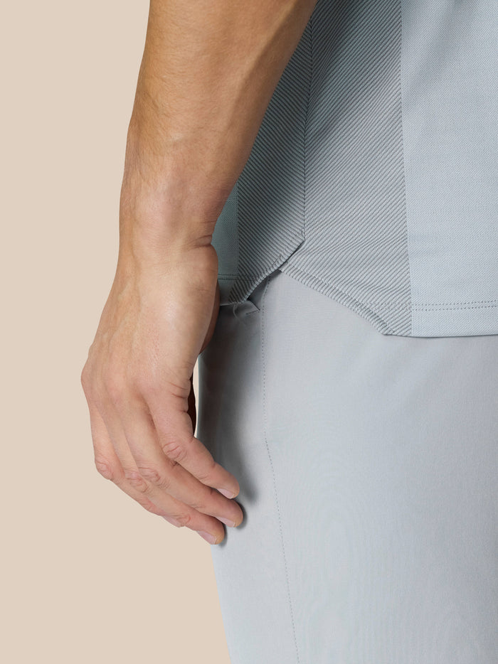 Side profile of a man in Pinnacle LVS Polo mid grey highlighting side panels and vent detailing.