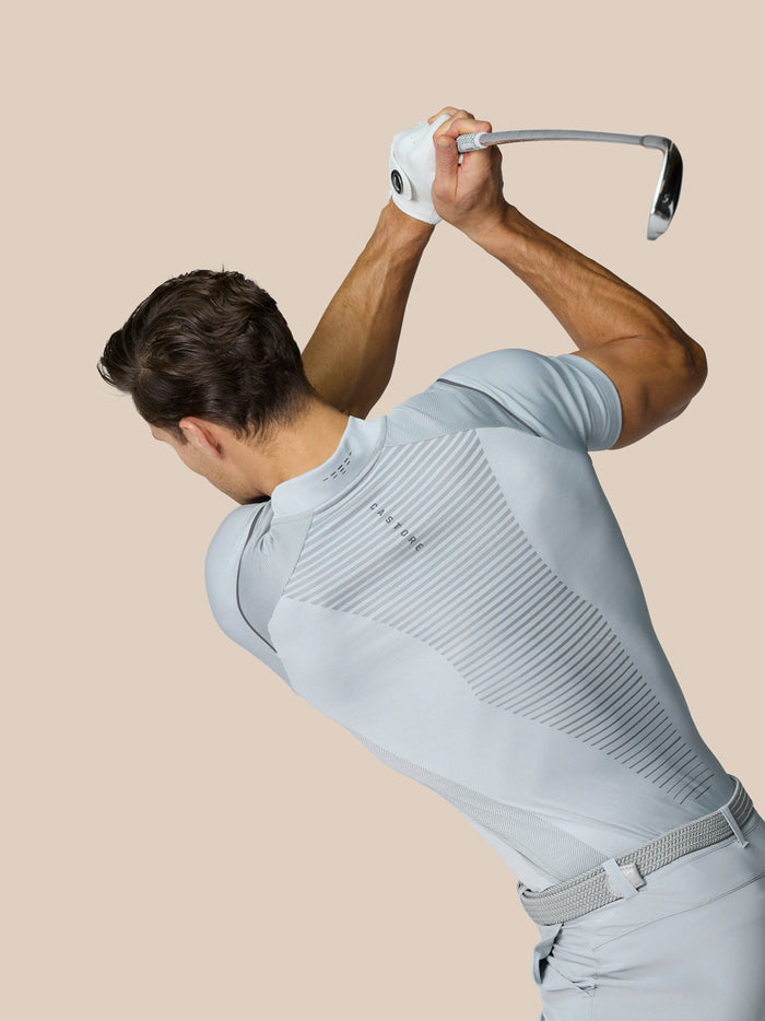 Golfer wearing Pinnacle LVS Polo in mid grey during a swing, showcasing vented knit and back panel.