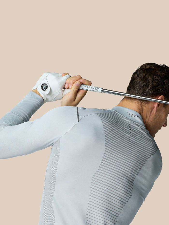 Golfer from behind wearing the Pinnacle LVS 1/4 Zip Top in mid grey while gripping a club across the shoulders.