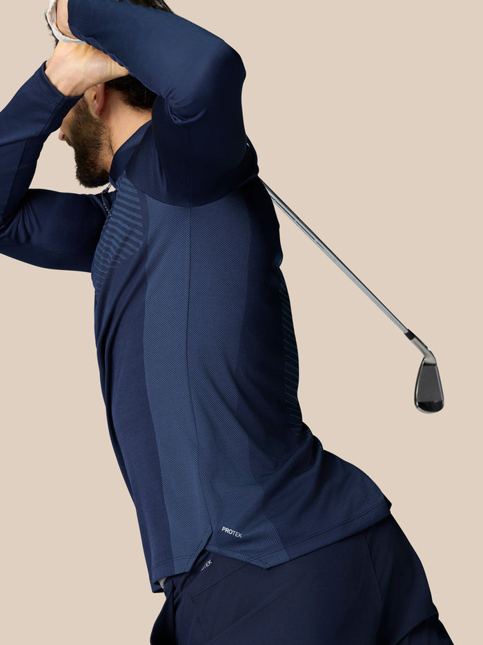 Male golfer wearing navy Pinnacle LVS 1/4 Zip Top with a golf club visible nearby