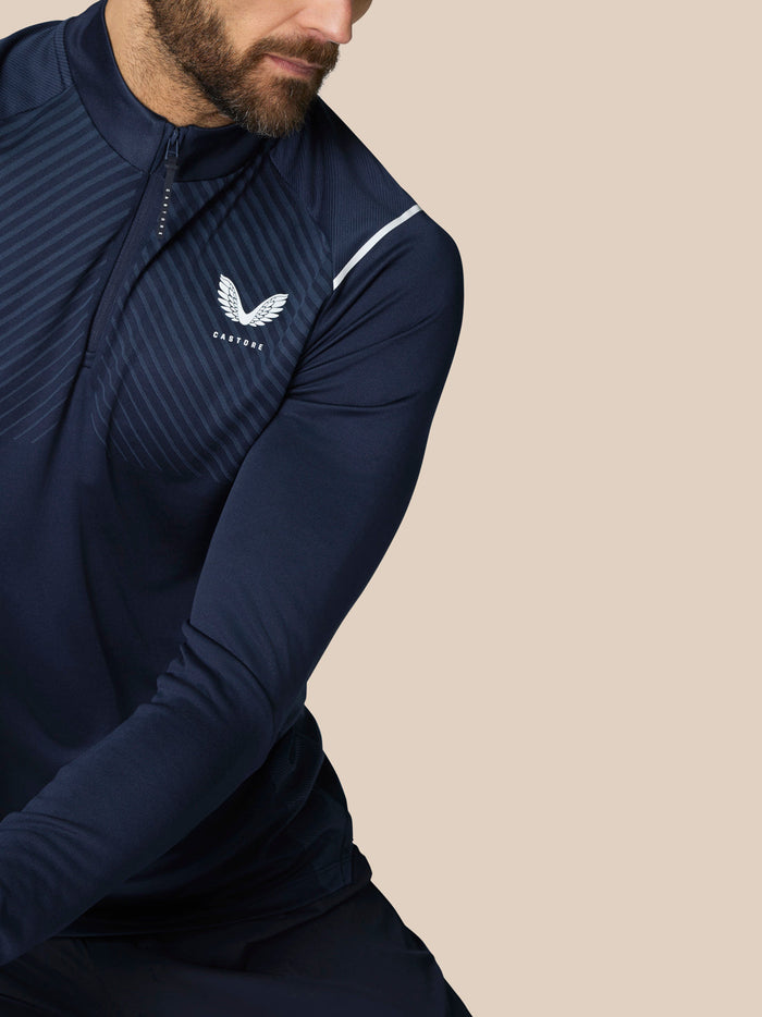 Close up of navy Pinnacle LVS 1/4 Zip Top chest area with Castore logo and diagonal stripes