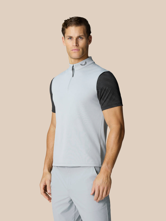 Male model wearing light grey Club Classic half zip golf gilet with high collar and black dotted sleeves.