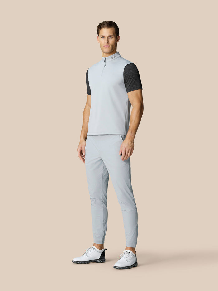 Full-length shot of a male model in a light blue golf top with dark patterned sleeves and light pants