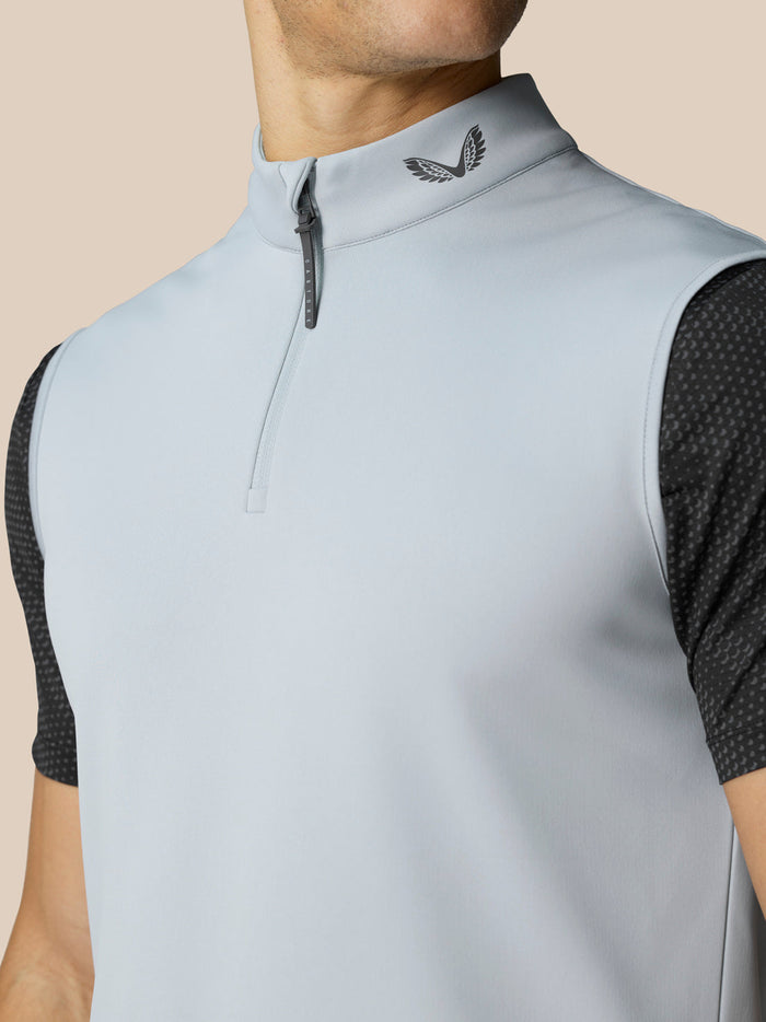 Close up of the gilet neckline showing a short zip and Castore logo on the collar against pale grey fabric.