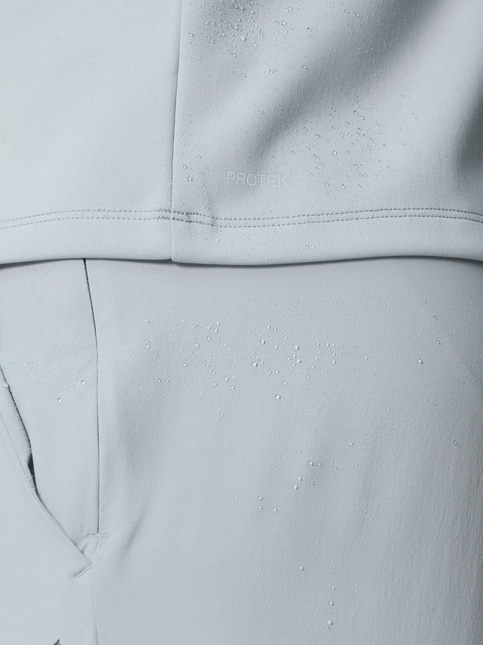 Close-up of light grey fabric with water droplets showing the ProTek finish on Club Classic Half Zip Gilet.