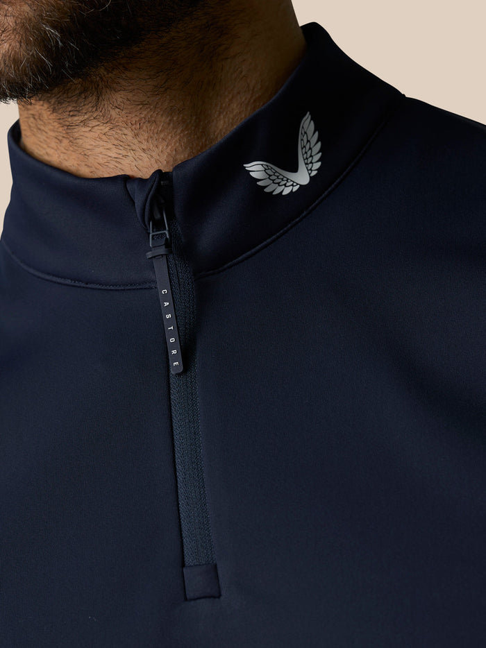 Close-up of navy gilet collar with white Castore wing logo and zip pull marked CASTORE
