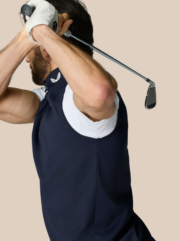 Athlete in navy Club 1/2 Zip Gilet sleeveless mid golf swing with a club