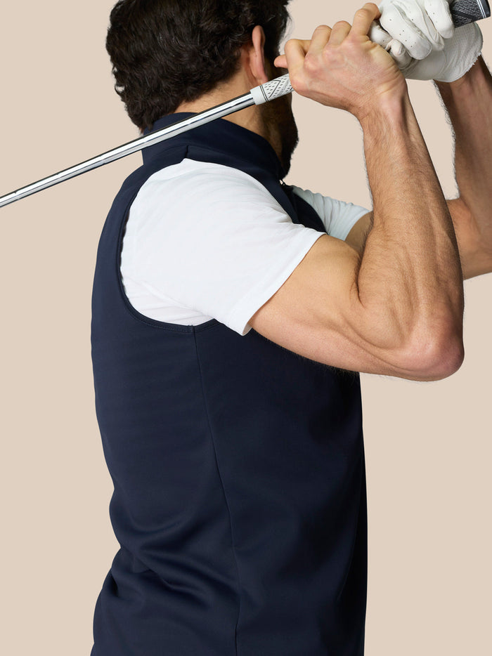 Side view of a male model wearing navy Club 1/2 Zip Gilet with a high neck and sleeveless design.