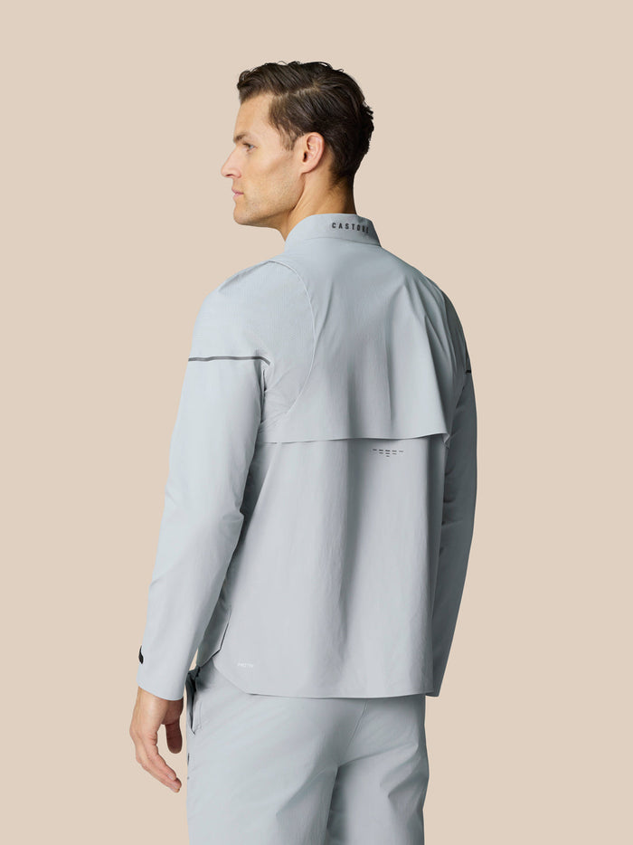 Male model wearing Golf Pinnacle LVS Woven Jacket in mid grey, back view with vented yoke and CASTORE logo on the collar.