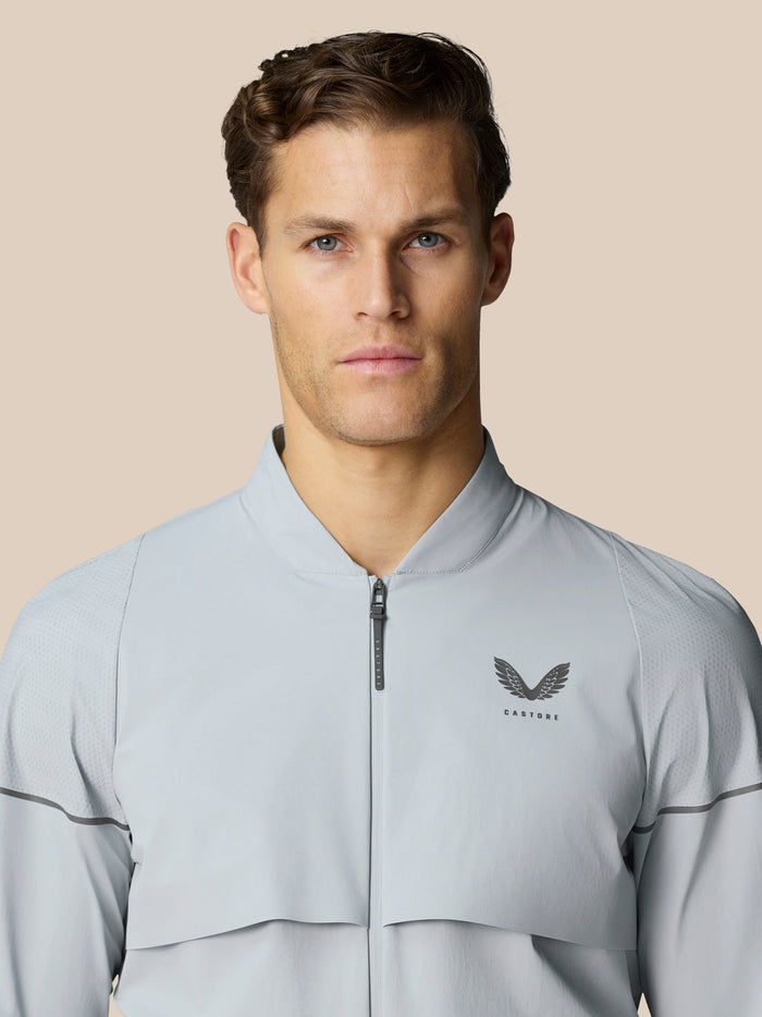 Model wearing Golf Pinnacle LVS Woven Jacket in mid grey showing front zip and Castore wing logo on the chest
