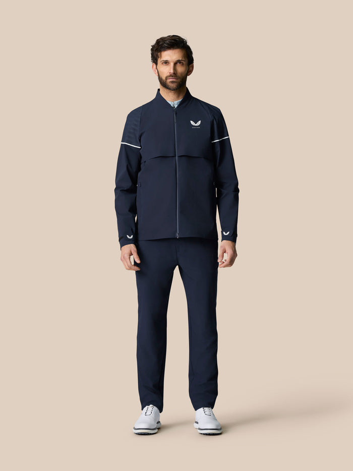 Male model wearing Golf Pinnacle LVS Woven Jacket in midnight navy with front zipper and venting panels.