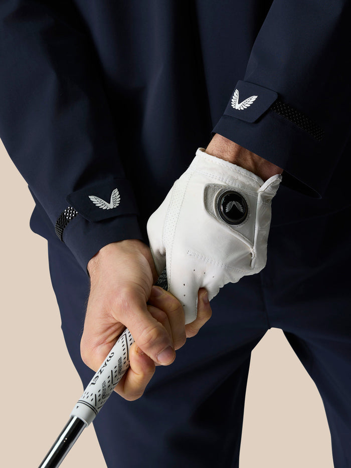 Close-up of a golfer gripping a club wearing the Midnight Navy LVS woven jacket with a white glove