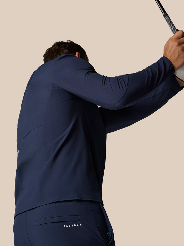 Athlete wearing navy Golf Pinnacle Winter Trousers with Castore logo on the back pocket and a golf club raised overhead.
