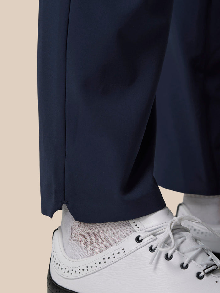 Close-up of navy winter golf trousers hem above white golf shoes