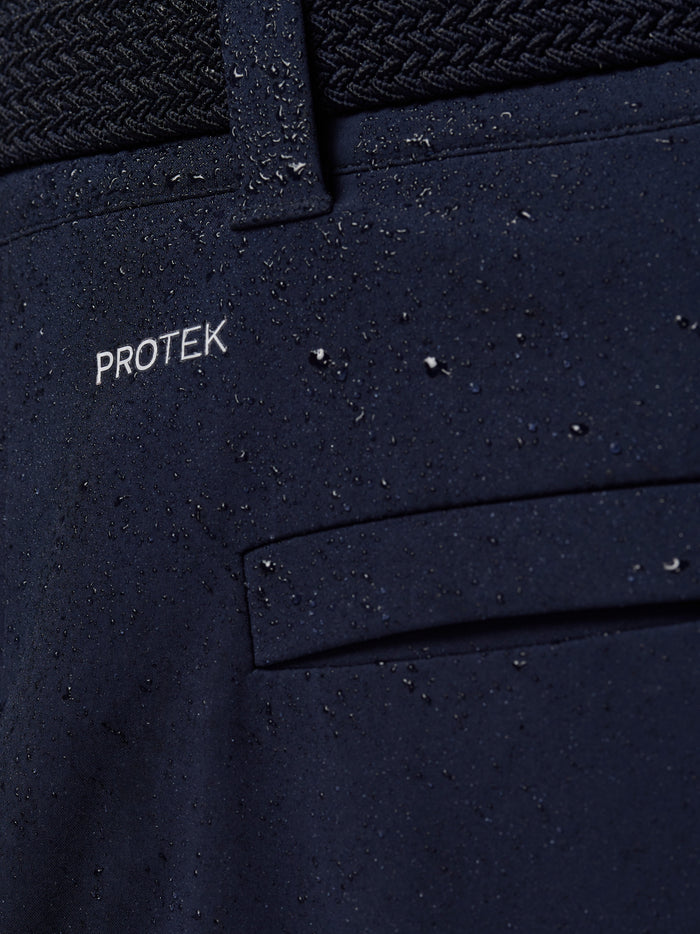 Close-up of navy trouser fabric with water droplets and ProTek branding.
