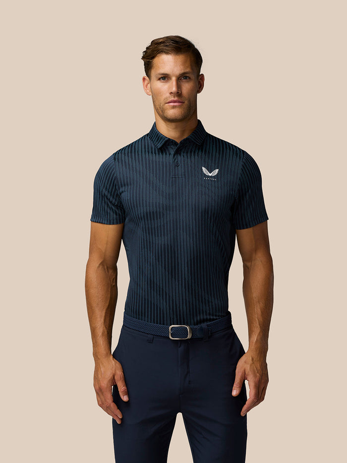 Male model wearing midnight navy Golf Pinnacle Glow Polo with striped knit and Castore logo on the left chest.