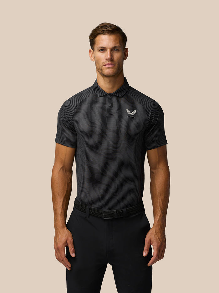Male model wearing a dark grey printed golf polo with three button placket and Castore logo on the left chest.