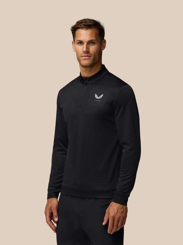 Male model wearing black Golf Club Classic 1/4 Zip Debossed Top with all over print and Castore chest logo