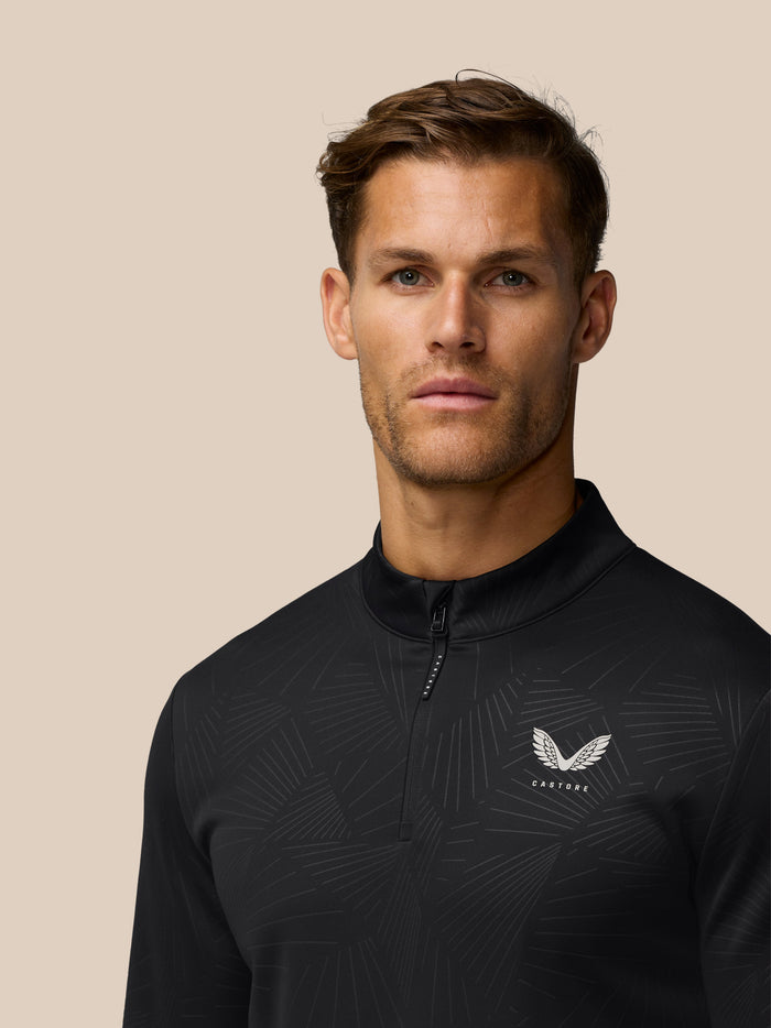 Front view of a man wearing the Castore Golf Club Classic 1/4 Zip Debossed Top in black with allover print and a wing logo on the chest