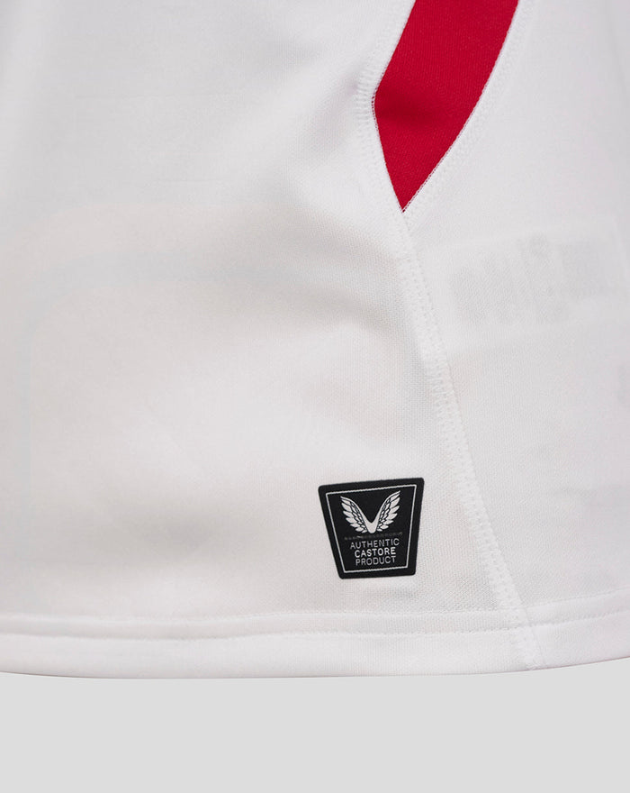 Close up of white England rugby shirt showing red side trim and authentic Castore product badge near the hem.