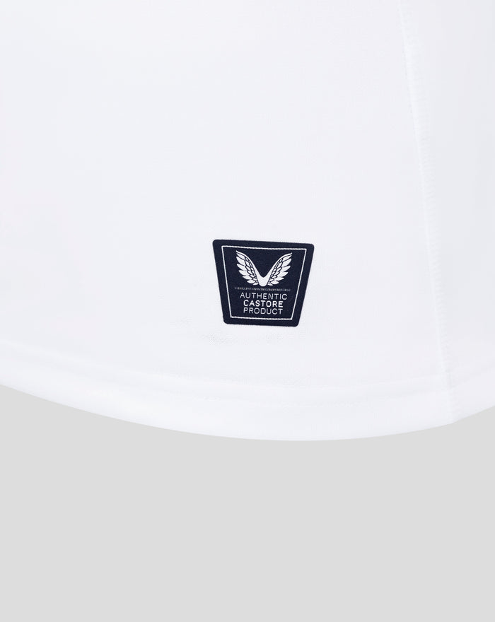 Close up of white England rugby shirt fabric showing a dark shield patch with wings and Castore branding.