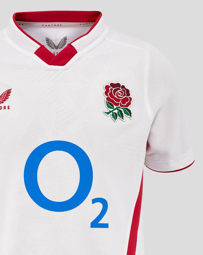 Close up of white Junior England Rugby Home Pro shirt front showing Rose crest left, O2 logo center, and Castore logo right with red collar trim.