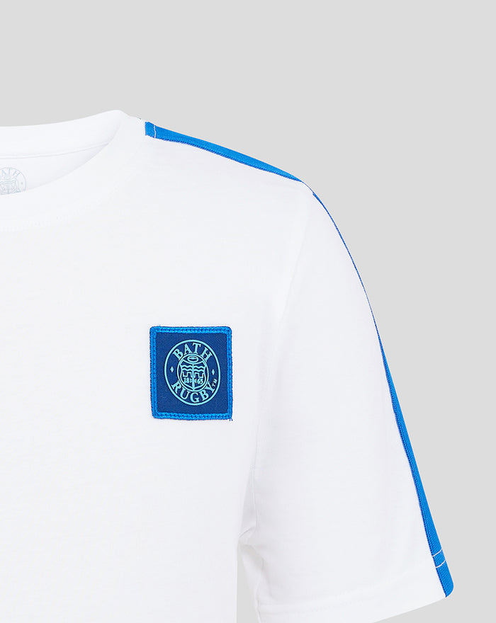 Shoulder close up of white junior T shirt showing blue piping and Bath Rugby crest patch on the chest