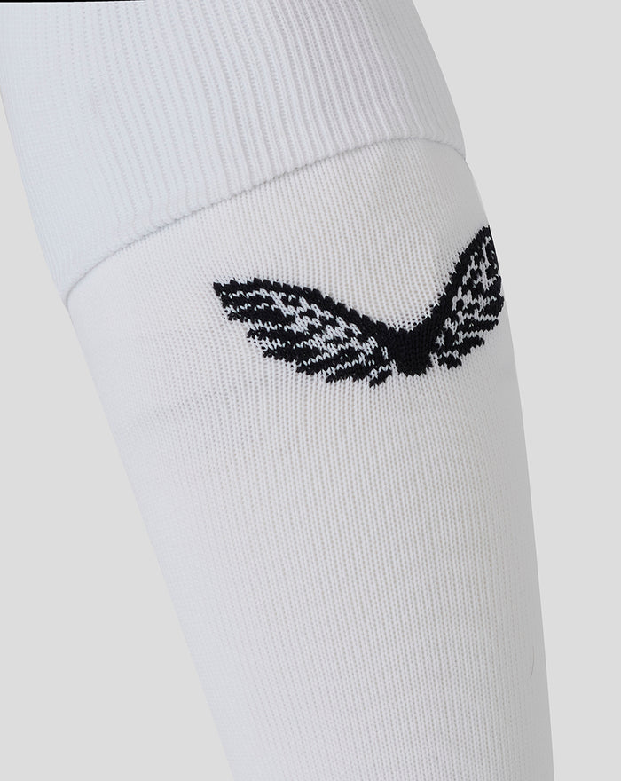 Close up of a white knee high rugby sock featuring a black embroidered emblem.