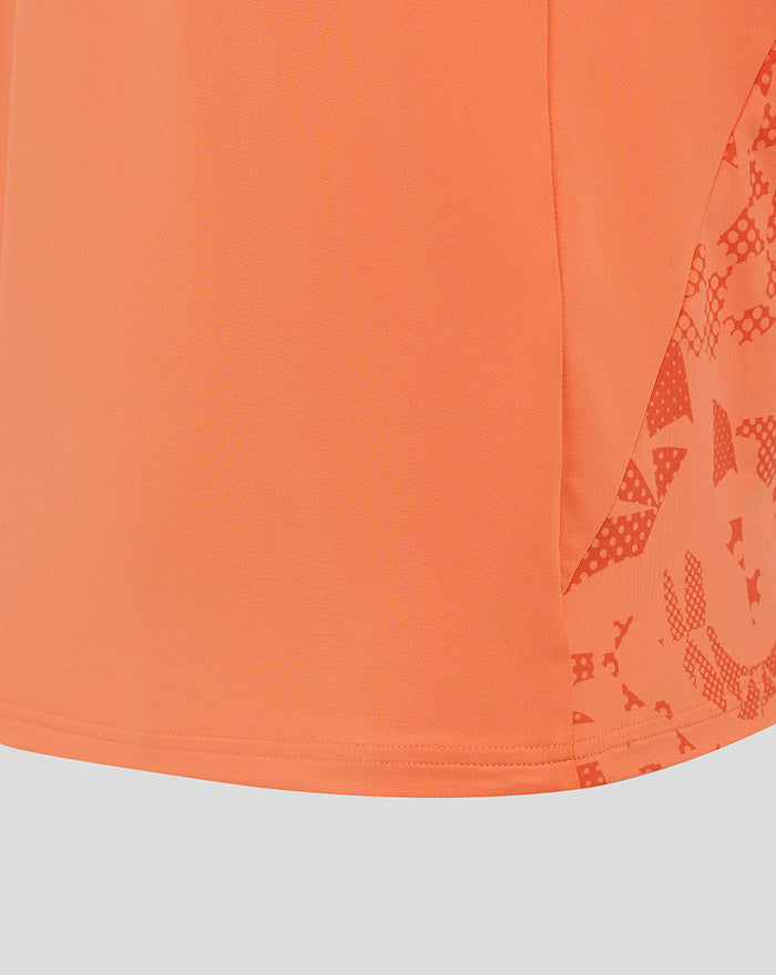 Close up of hem and side panel on melon England Cup midlayer top, showing abstract sleeve print and curved lower edge