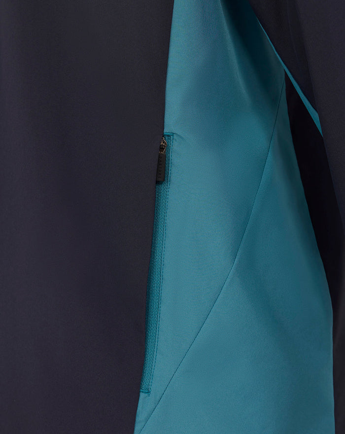 Close up of teal side panel and zip pocket on navy long sleeve shower jacket