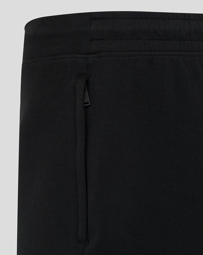 Close-up of black travel shorts showing elastic waistband and side zip pocket