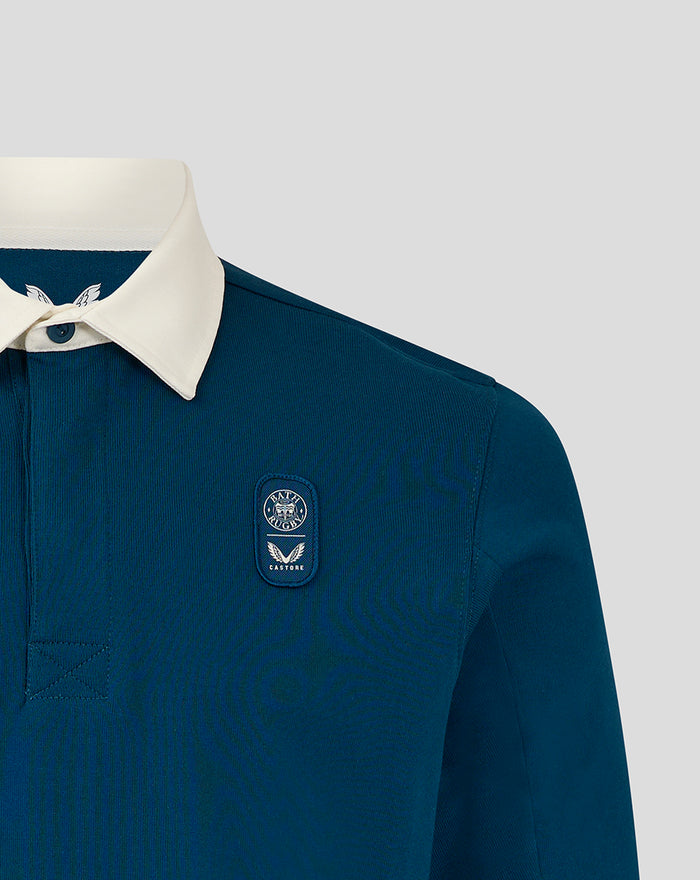 Close up of teal rugby shirt with white collar and left chest badge.