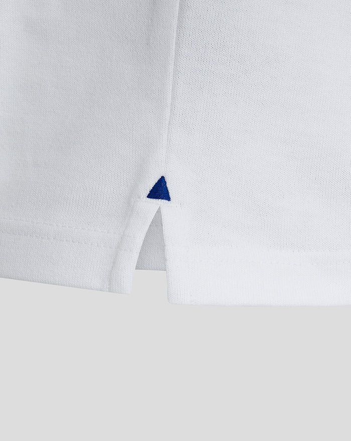 Close up of white rugby shirt fabric with a small blue triangle embroidery at the side slit